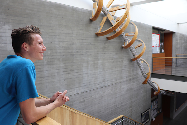 Smiling student ambassador leaning on a rail in the Middleton Science Center.