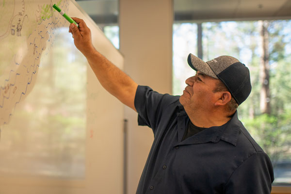 GED Prep or English Language Learner Student Drawing a Fishing Scene on Whiteboard