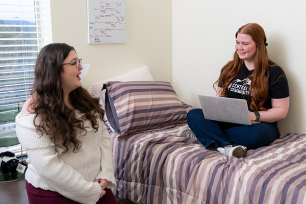 Two students laugh together in a residence hall room