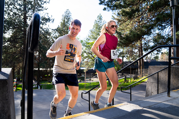 two people running up stairs giving thumbs up