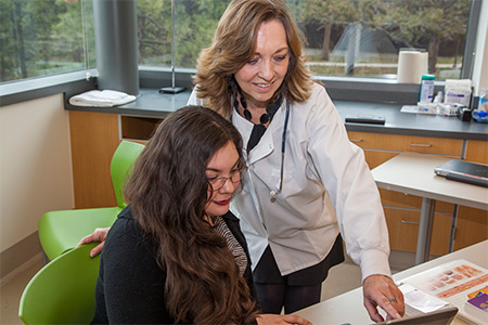 One woman pointing something out on a laptop to a student.