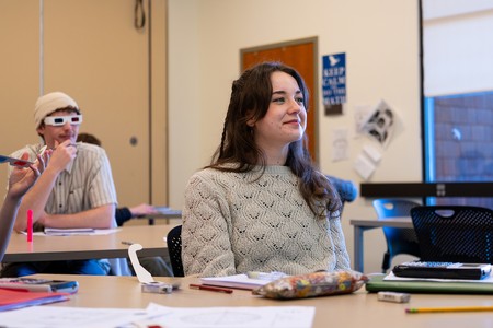 Students in a COCC math class look toward the front of the room, some wearing 3D glasses during a lecture on multivariable calculus.