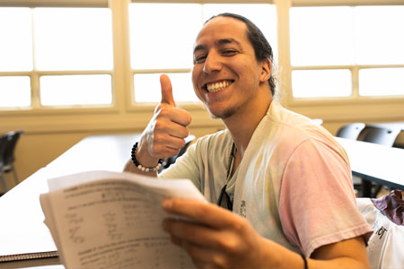 A COCC student gives a thumbs up while reviewing a math assignment in class.