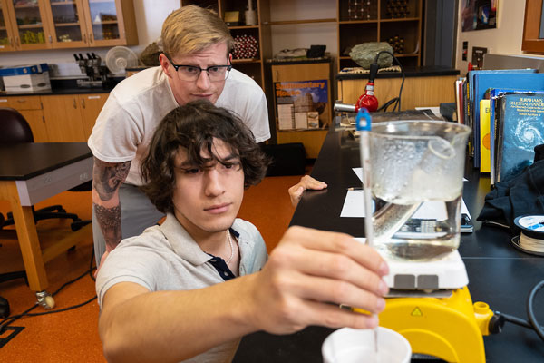 Physics students measuring fluid in a lab
